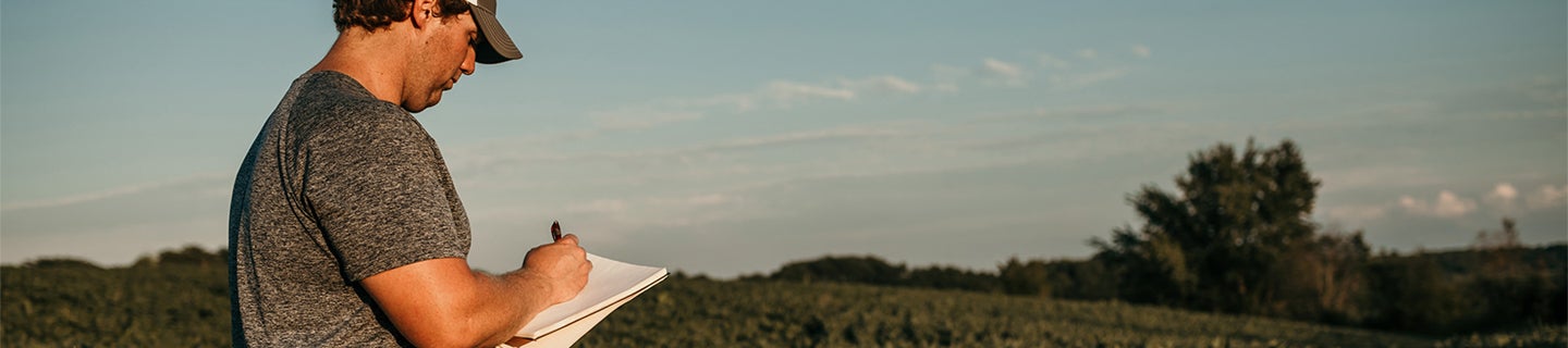 Man with notebook in a field.